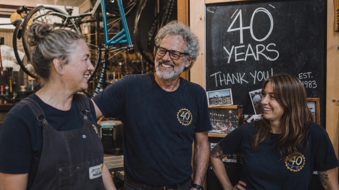 Long-standing staff and the owner gathered informally in their shopfront, genuine relaxed moment — a sample milestone anniversary film.