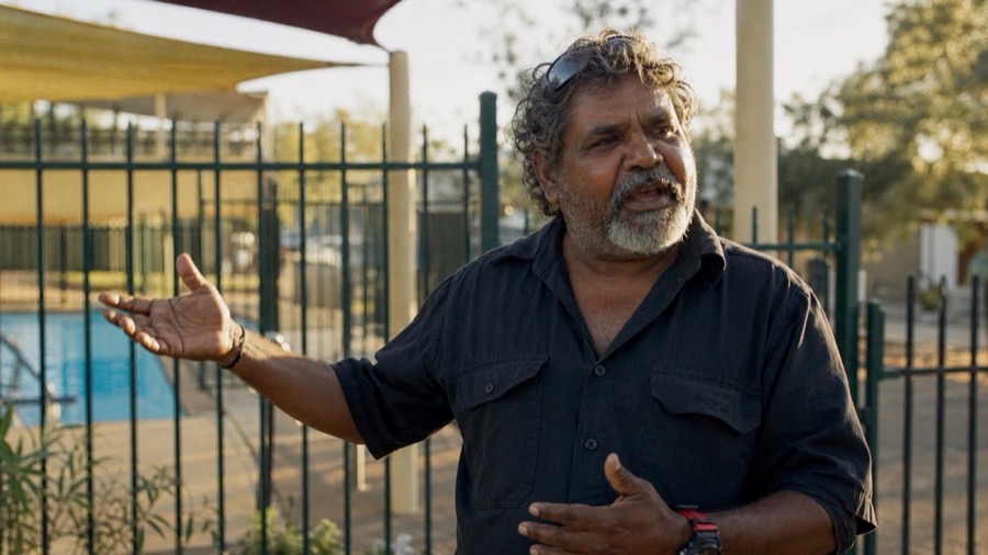 An Aboriginal Australian community organiser at the local space he helped create, mid-story, warm late-afternoon light — the changers who made it happen.